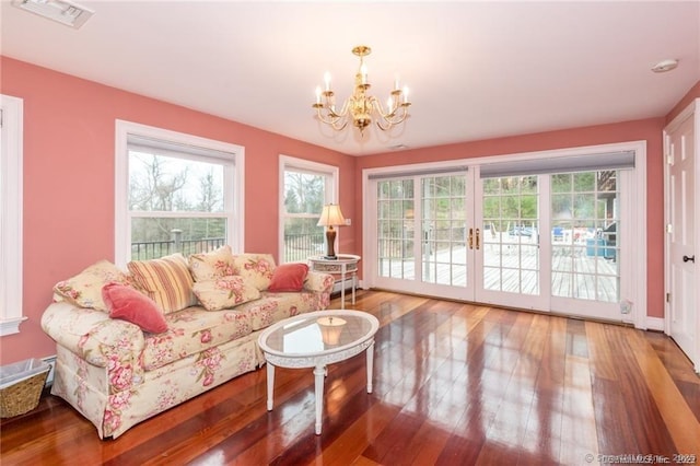 living room with french doors, a baseboard heating unit, hardwood / wood-style floors, and a notable chandelier