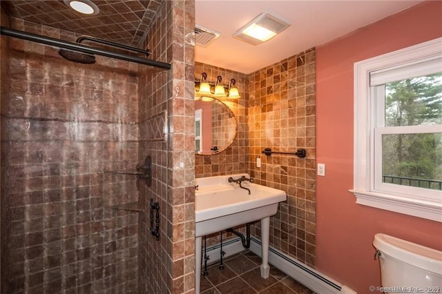 bathroom featuring tiled shower, toilet, tile patterned flooring, and tile walls