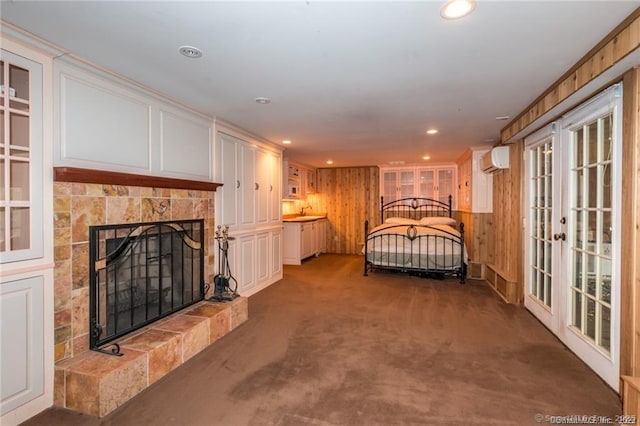 bedroom with french doors, a tiled fireplace, dark carpet, access to outside, and an AC wall unit