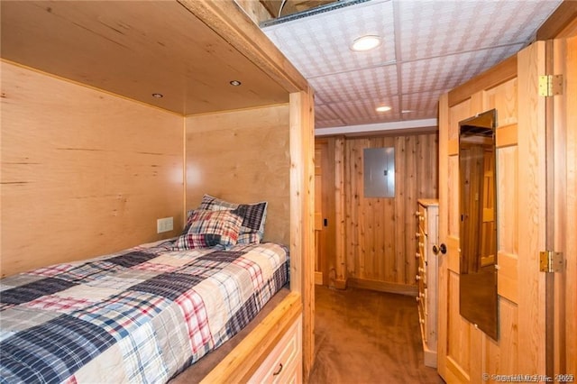 bedroom featuring carpet, electric panel, and wood walls