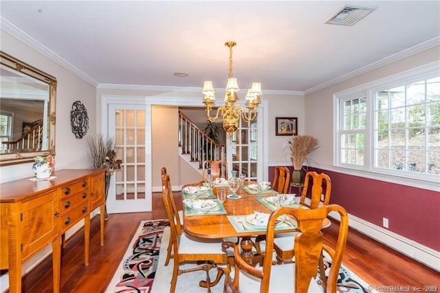 dining room with wood-type flooring, ornamental molding, and a chandelier