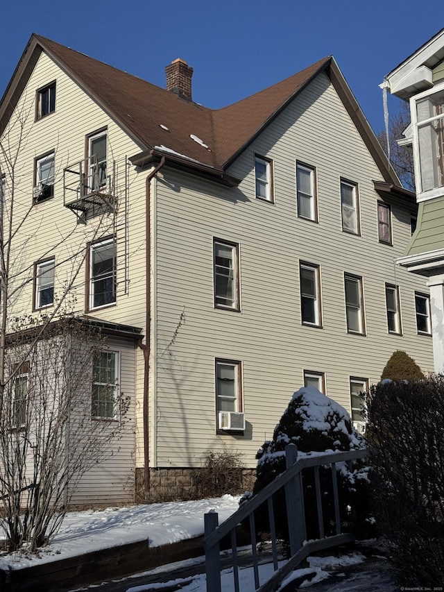 view of snow covered exterior featuring a chimney and cooling unit