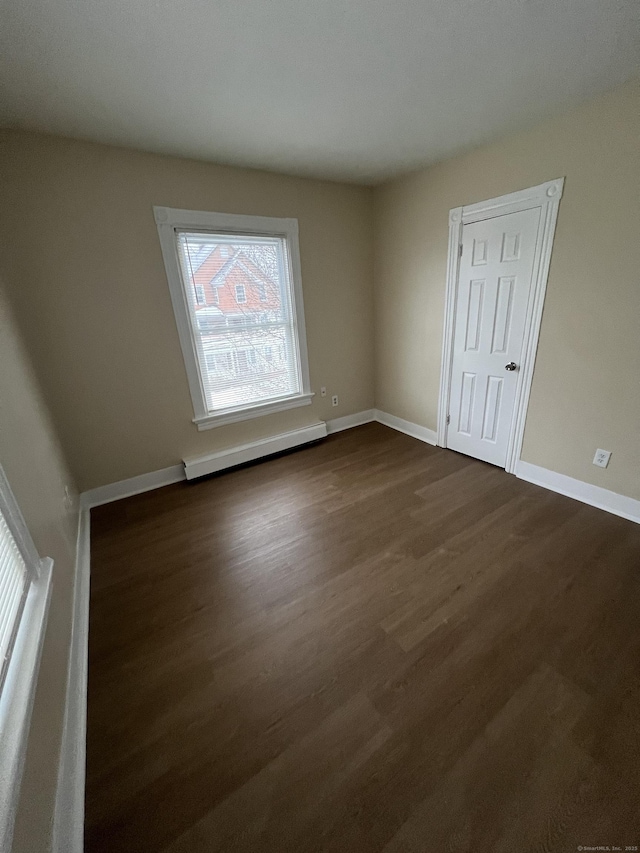 spare room featuring a baseboard radiator and dark wood-type flooring