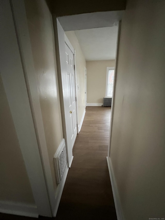 corridor with hardwood / wood-style flooring and radiator heating unit