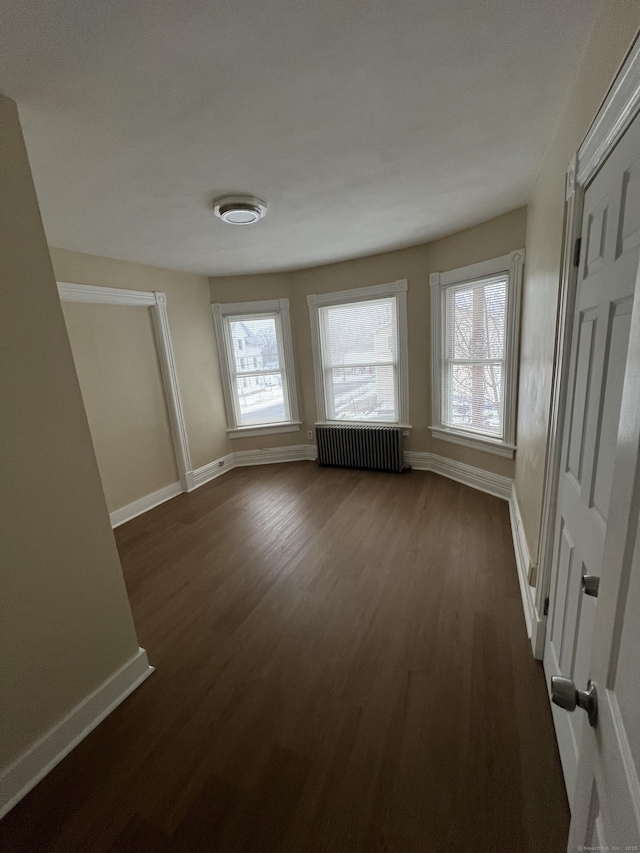 unfurnished room featuring radiator heating unit and dark hardwood / wood-style floors