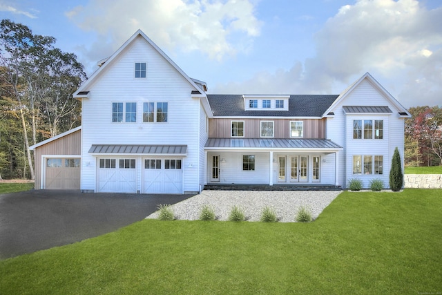 rear view of house featuring a yard, a shingled roof, covered porch, an attached garage, and a standing seam roof