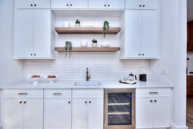 kitchen featuring beverage cooler, light countertops, white cabinetry, open shelves, and a sink