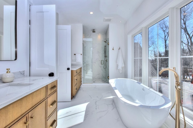 bathroom with marble finish floor, two vanities, a freestanding tub, and a marble finish shower