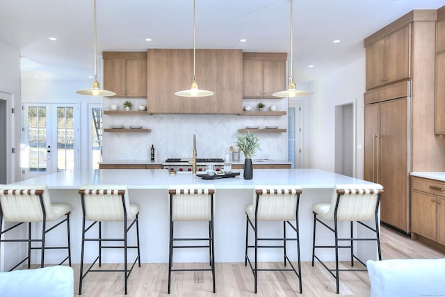 kitchen featuring a breakfast bar, paneled built in refrigerator, open shelves, and light countertops