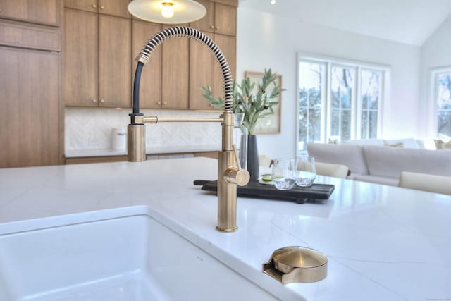 interior details featuring brown cabinetry, tasteful backsplash, light countertops, and a sink