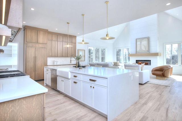 kitchen with white cabinets, an island with sink, light countertops, pendant lighting, and a sink