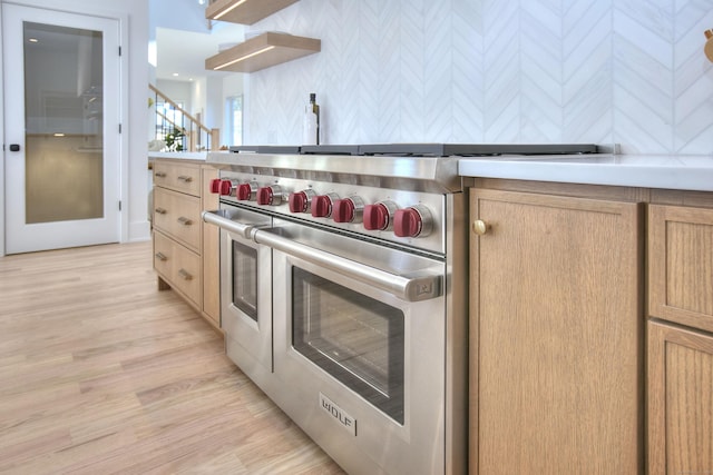 kitchen with light wood-style floors, designer stove, light countertops, and light brown cabinetry