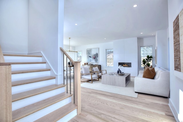 stairs with wood finished floors, a tile fireplace, and recessed lighting