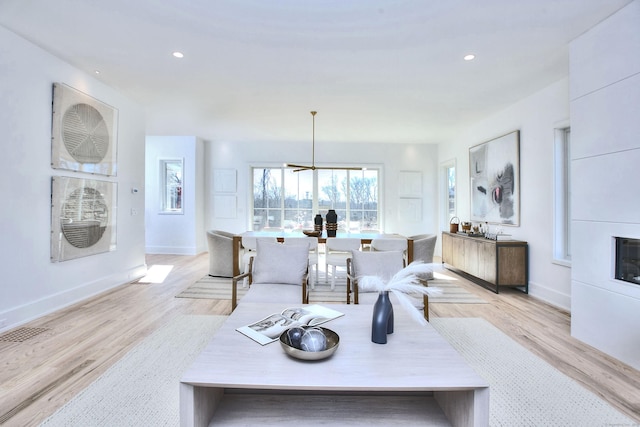 living room featuring light wood-style floors, recessed lighting, visible vents, and baseboards