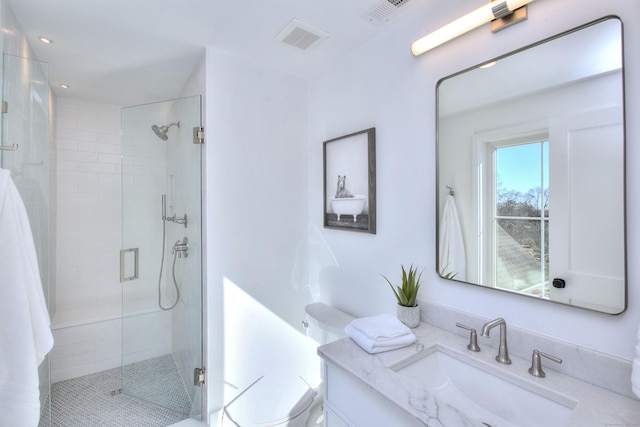 bathroom with visible vents, toilet, a shower stall, and vanity