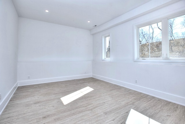 spare room featuring light wood-type flooring, baseboards, and recessed lighting