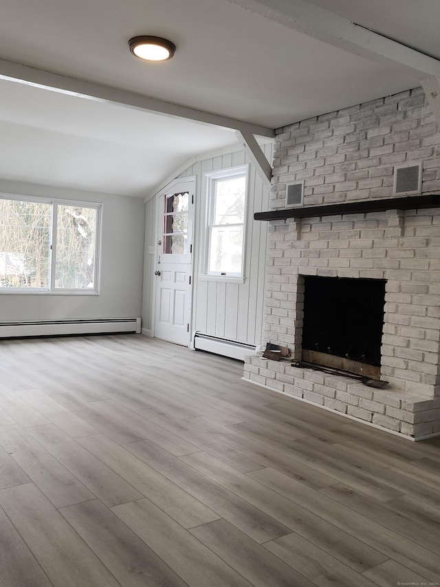 unfurnished living room featuring a baseboard heating unit, lofted ceiling with beams, and a healthy amount of sunlight