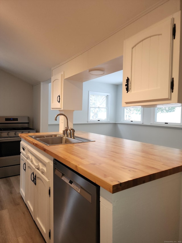 kitchen featuring white cabinets, a sink, butcher block countertops, stainless steel appliances, and wood finished floors