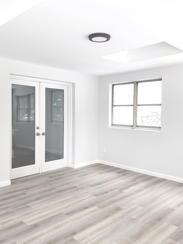 empty room featuring french doors, light wood-style flooring, and baseboards