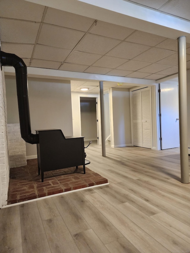 finished below grade area featuring baseboards, wood finished floors, and a paneled ceiling