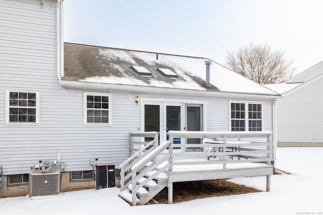 snow covered house featuring central air condition unit and a wooden deck