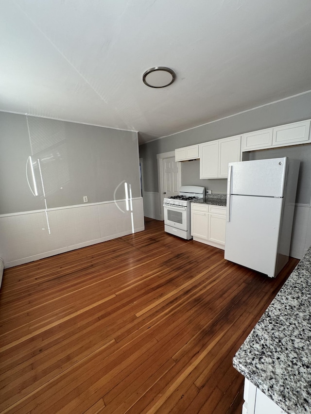 kitchen with white cabinetry, white appliances, dark wood-type flooring, and light stone counters