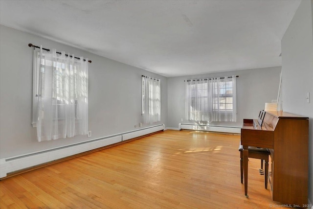 interior space with light wood-type flooring, a baseboard radiator, and a baseboard heating unit