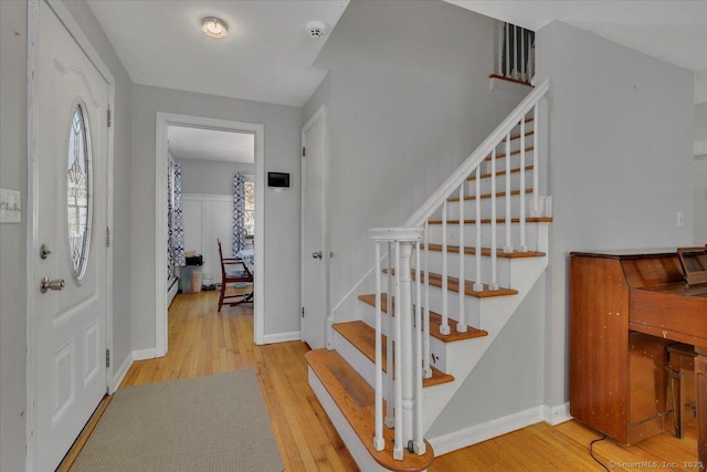 entrance foyer featuring light wood-type flooring, stairs, and baseboards