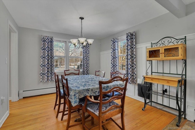 dining space featuring light wood-type flooring, an inviting chandelier, and a baseboard heating unit