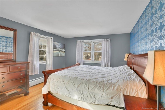 bedroom with light wood finished floors and a baseboard radiator