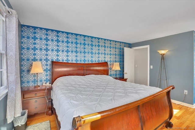 bedroom featuring baseboards, light wood finished floors, and wallpapered walls