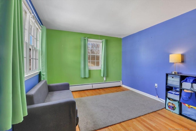 living area with baseboard heating, wood finished floors, and baseboards