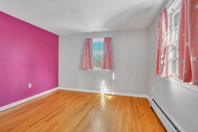 unfurnished room featuring a baseboard radiator, baseboards, and light wood finished floors