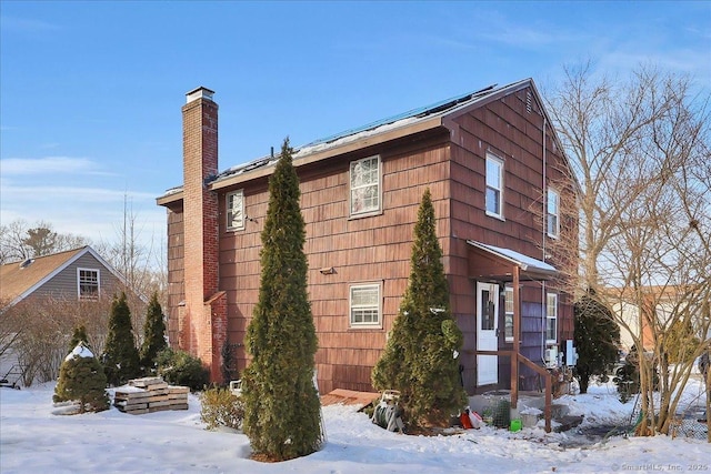 view of snowy exterior with a chimney