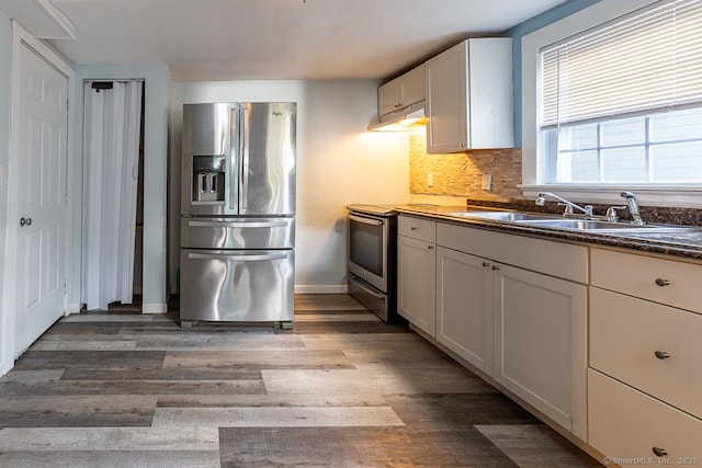 kitchen with hardwood / wood-style floors, tasteful backsplash, sink, white cabinets, and stainless steel appliances