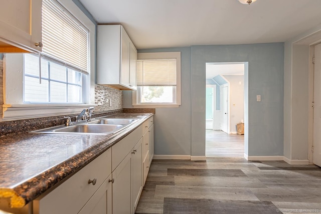 kitchen with sink, white cabinets, backsplash, and light hardwood / wood-style flooring