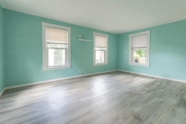 spare room featuring plenty of natural light and light hardwood / wood-style floors