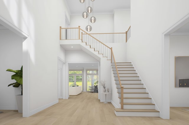 stairs with hardwood / wood-style floors, a towering ceiling, and ornamental molding