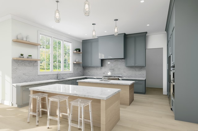 kitchen with gray cabinets, hanging light fixtures, a kitchen breakfast bar, light stone countertops, and an island with sink