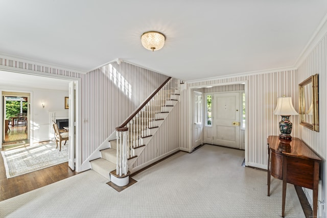 entryway featuring crown molding, a wealth of natural light, a fireplace, and stairway