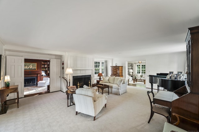 living area with ornamental molding, a fireplace, and light colored carpet