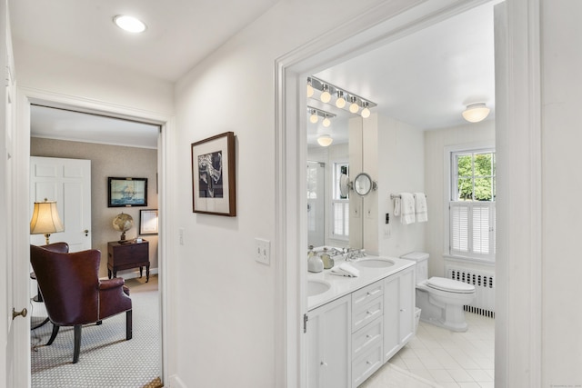 full bath featuring double vanity, radiator, toilet, tile patterned flooring, and a sink