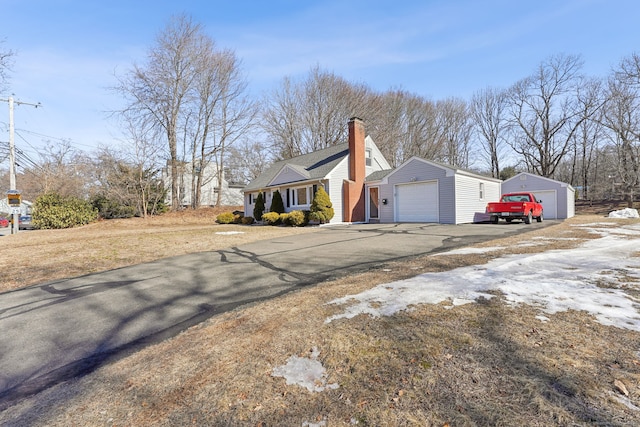 view of side of property featuring a garage, an outbuilding, and a chimney