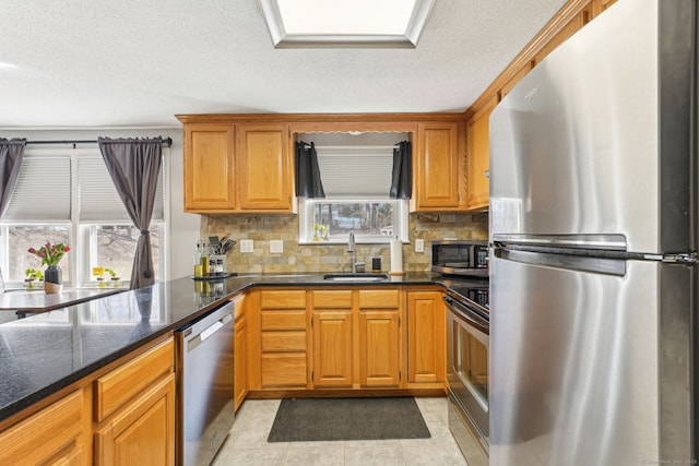 kitchen with appliances with stainless steel finishes, backsplash, plenty of natural light, and a sink