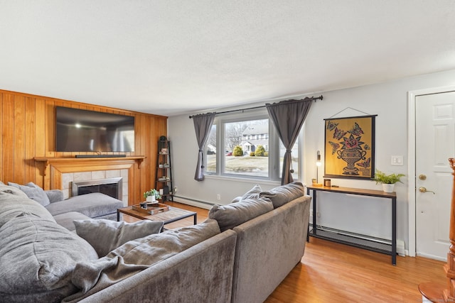 living room with light wood-style floors, a fireplace, baseboards, and baseboard heating