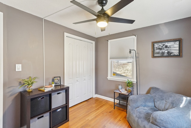 living area featuring light wood-style floors, ceiling fan, and baseboards