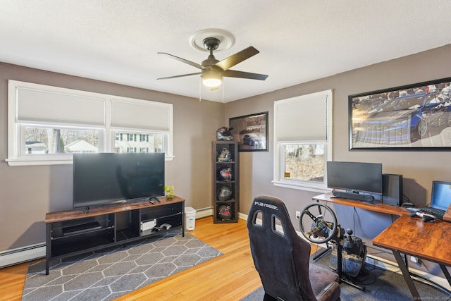 office featuring baseboards, ceiling fan, a baseboard heating unit, and wood finished floors