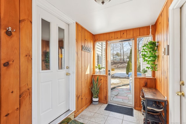 doorway to outside featuring wood walls and light tile patterned flooring