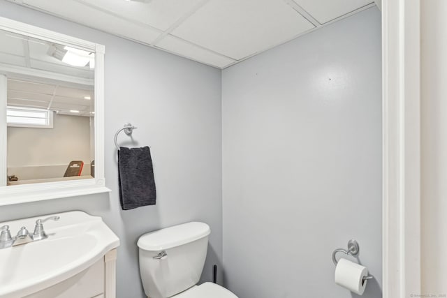 half bath with toilet, vanity, and a paneled ceiling