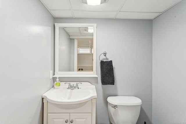 bathroom featuring toilet, a drop ceiling, and vanity